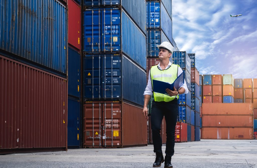 Foreman holding document, walking and checking the containers box from cargo ship for export and import